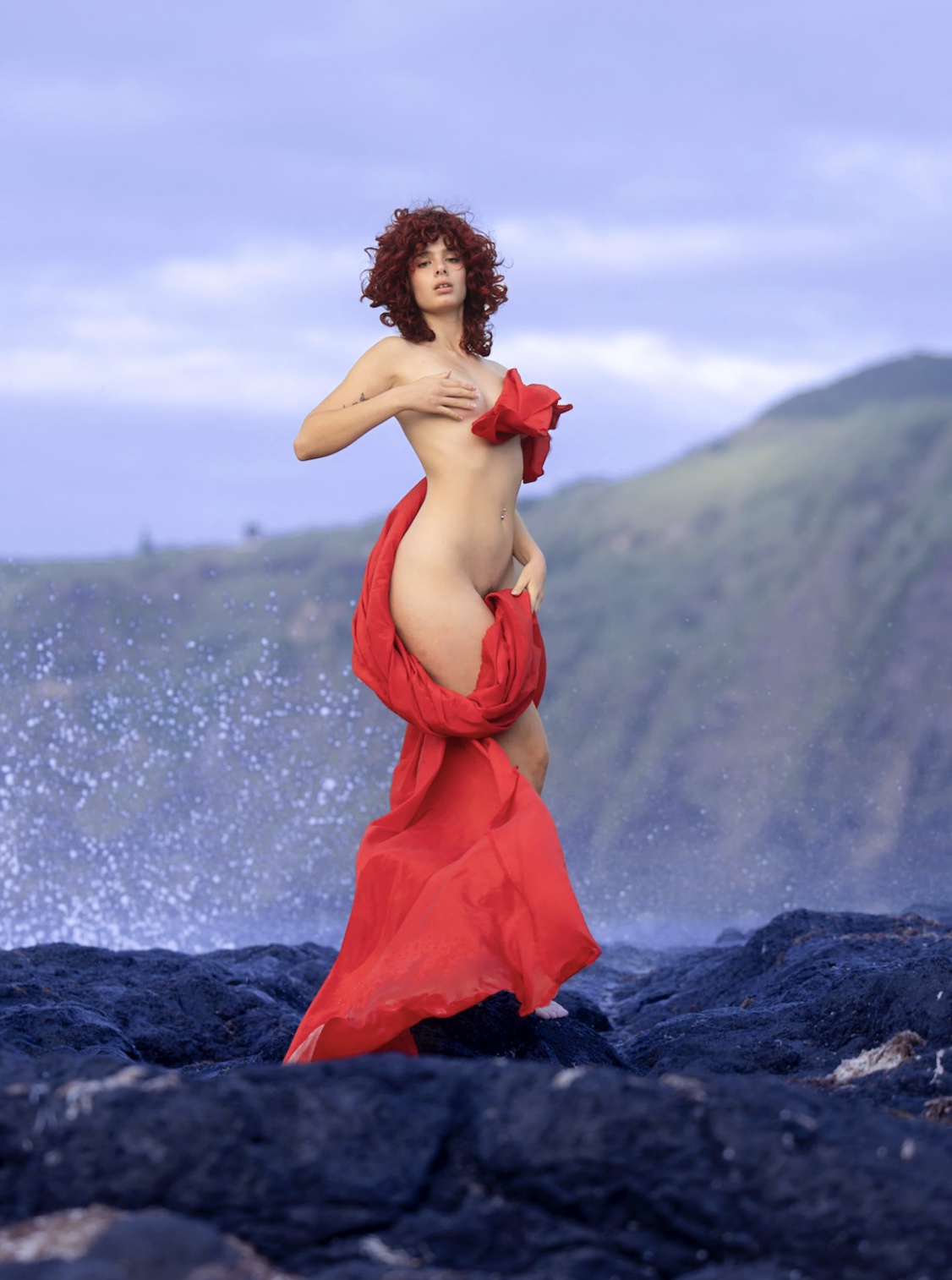 A standing figure with red fabric against the sky