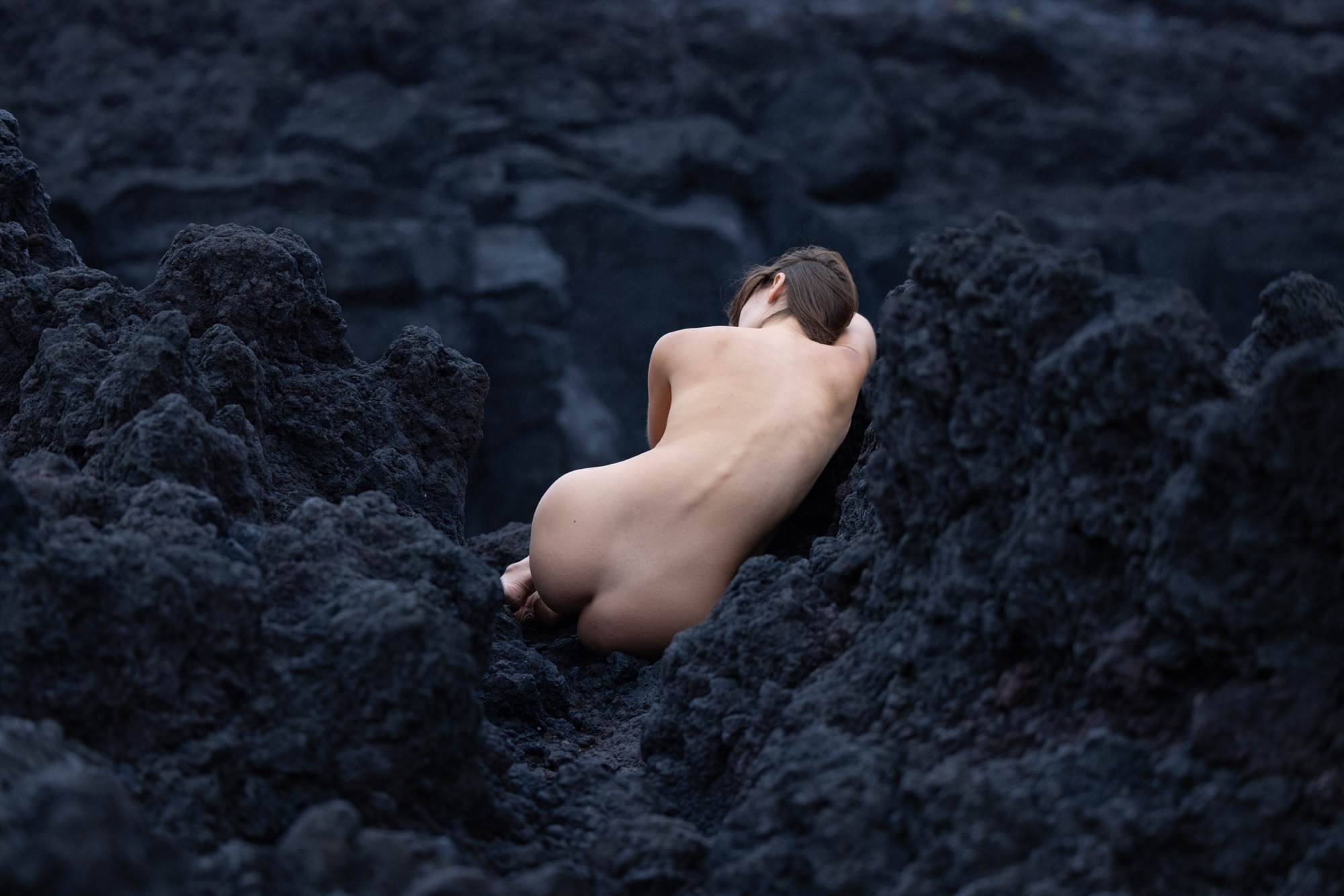 A figure resting on black lava rock